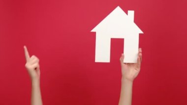 Beyaz Saray 'ın modelini tutan kadın eli iyi bir jest yapıyor, emlak evi onayı alıyor, reklam için fotokopi alanı olan kırmızı renkli arka plan duvarının üzerinde izole edilmiş. Ev hakkındaki sosyal servisi kabul et