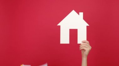 Beyaz kağıt ev ve megafona, ev kredisi satışı kirası mülkiyet bilgilerine stüdyodaki kırmızı arka planda izole edilmiş kadınlara yakın durun. Emlak pazarlama ve ipotek kavramı