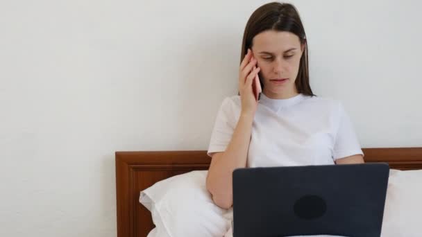Jovem Mulher Falando Telefone Usando Laptop Sentado Cama Confortável Casa — Vídeo de Stock