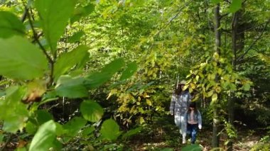 Güzel bir okul kızıyla gezen ve yürüyüş sırasında etrafa bakınan genç anne hayrete düştü. Beyaz bir aile ulusal sonbahar parkında gezintiye çıkıyor. İyi yolculuklar. Gezgin yaşam tarzı konsepti.