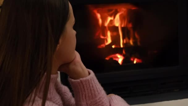 年轻的高加索女人有选择地坐在靠近壁炉的舒适的地板上休息 黑发女孩看着火光 享受着周末在现代乡村别墅里度过的时光 闲暇时间 休息概念 — 图库视频影像