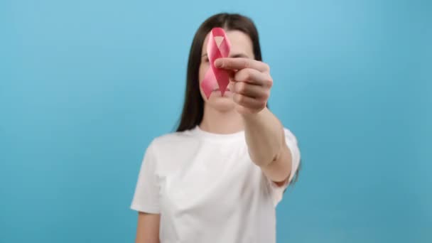 年轻美丽的高加索女性形象20多岁的T恤显示粉红缎带 模特摆出蓝色背景 预防和乳腺癌意识概念 有选择的重点 — 图库视频影像