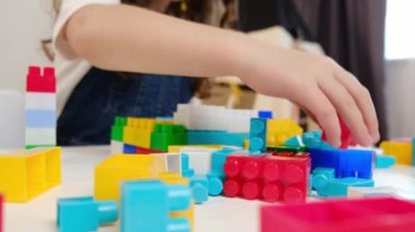 Küçük kızın seçici odak noktası evde plastik blok oynamak. Okul kızı oturma odasında oturmuş eğleniyor, tasasız çocukluk zamanlarının tadını çıkarıyor. Hobi, çocuk eğlencesi konsepti.