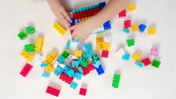 幼童在幼儿园白桌旁玩耍塑料构造者的俯瞰近景 女孩玩彩色积木 教育玩具很开心 游戏与童年概念 — 图库视频影像