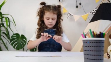 Evde hobi, yaratıcı çocuk konsepti. 6 'lı yaşlardaki küçük kızlar rahat bir oturma odasında çadırın yanında otururlar. En sevdikleri meşgaleye gömülürler. Çizim defterine kalem çizerler, resim yaparlar.