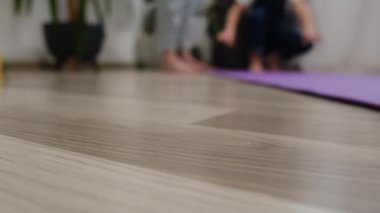 Küçük kızı olan genç annenin seçici odağı hazırlanmak için yoga minderi serer, birlikte zaman geçirirler. Formda spor ailesi, salgın hastalık salgını sırasında evdeki oturma odasında yoga yaparak egzersiz yapıyor.