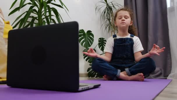 Close Mindful Pretty Little Uczennica Robi Jogę Oglądanie Lekcji Online — Wideo stockowe