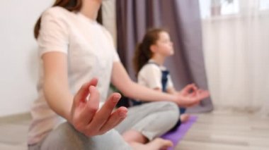 Nilüfer çiçekli evde oturan küçük kızı olan sağlıklı bir annenin seçici odağı derin derin nefes alma, denge, uyum ve stres olmadan meditasyon yapıyor. Ruh sağlığı konsepti