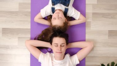 Sağlıklı, sakin, genç bir anne ve mor bir mindere uzanmış, elleri başının arkasında uzanmış, dinlenmiş, temiz hava soluyan, evde stres yapmayan bir kız çocuğu. Huzurlu aile uykusu
