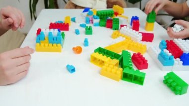 Genç anne ve küçük kızın evde plastik blok oynadığı seçmeli bir odak noktası. Aile, pofuduk ayılarla aynı masaya oturur, eğlenir, tasasız çocukluk zamanlarının tadını çıkarır. Hobi, hobi eğlence konsepti.