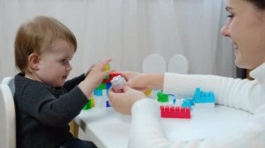 Sevgi dolu bir anne, küçük kızıyla aynı masada otururken kızına renkli bloklardan bir kule yapmayı öğretiyor. Aile evde boş vakit geçiriyor. Oyuncak setiyle eğleniyor. Çocuk gelişimi, eğlence kavramı