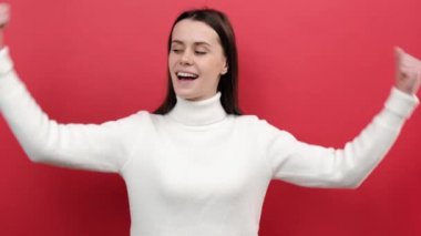 Eğlenceli genç kadın 20 'li yaşlarda, başarılı olma hırslarını ifade eden, beyaz süveter giymiş, kırmızı arka plan stüdyosunda soyutlanmış poz veren kadın hakları gösteren bisepsler gösteriyor. Feminizm kavramı