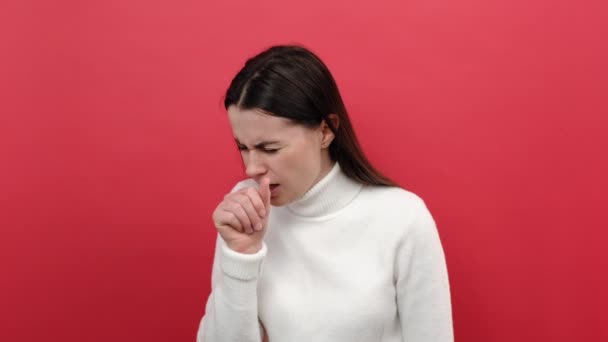 無病息災の若いブルネットの女性が笑って立って痛み インフルエンザの症状 肺の問題から眉をひそめて 赤い色の背景スタジオに隔離された白いセーターを着ています 喉の痛みの概念 — ストック動画