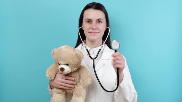 Retrato Linda Sonriente Joven Doctora Sosteniendo Estetoscopio Pequeño Oso Esponjoso — Vídeo de stock