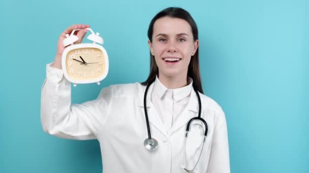 Retrato Bela Jovem Médico Segurando Despertador Mostrando Sinal Usa Uniforme — Vídeo de Stock