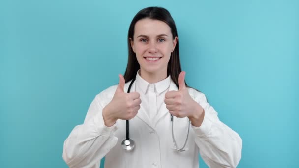 Feliz Sorrindo Jovem Médica Casaco Branco Com Estetoscópio Mostrando Sinal — Vídeo de Stock