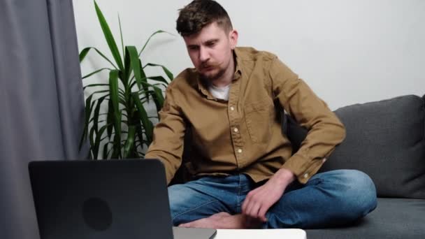 Fokuserad Ung Kaukasier Man Med Laptop Sitter Mysig Soffa Vardagsrummet — Stockvideo