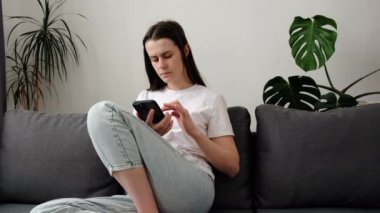 Stresli esmer kız cep telefonundaki mesajları okuduktan sonra ani sorunlar ya da ilişkiler üzerine düşünüyor. 20 'li yaşlardaki üzgün genç bir kadın elinde akıllı telefonuyla kötü haberlerle oturuyor.