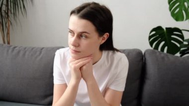 Düşünceli genç beyaz kadın kişisel ya da ilişki sorunları düşünür, mesafeye bakar oturma odasında yalnız başına kanepede otururken düşünceli hisseder. Hayat zor, karar ver.