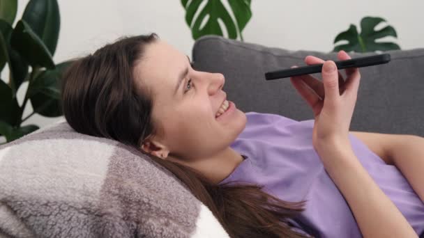 Genç Mutlu Esmer Kadın Rahat Kanepeye Uzanıp Akıllı Telefon Kullanıyor — Stok video