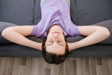Huzurlu, sakin, rahat, gri koltukta dinlenen genç bir kadın manzarası. Parlak, yalnız sabahın tadını çıkarıyor. Milenyum bayanı rahat bir kanepede dinleniyor, hafta sonu stressiz zaman geçiriyor.
