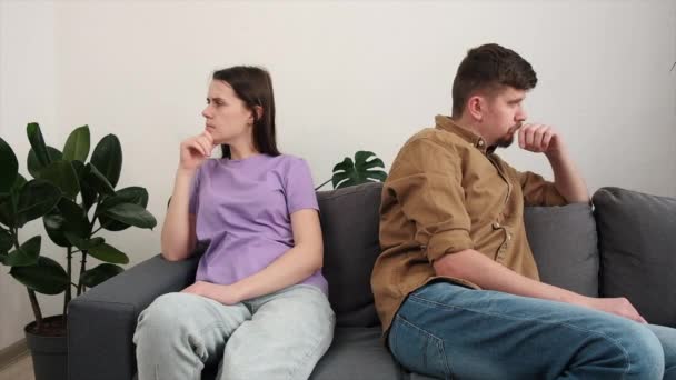 离了婚的夫妻无视对方 有误解 家庭关系问题的概念 坐在沙发上和生气的妻子分开的那个衣衫褴褛的年轻人 争吵之后不许说话 — 图库视频影像