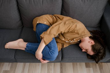 Kanepede kıvrılıp yatan yorgun ve mutsuz genç bayanın üst görüntüsü regl sancılarından muzdarip. Planlanmamış gebelik ve kürtaj. Hayattaki sorunlardan saklanarak uyumaya çalış. Ayrılma ve boşanma kavramı.