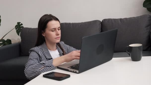 专注的年轻女性在家里用笔记本电脑坐在地板上 看着屏幕 阅读或写电子邮件 认真的黑发女学生做作业 研究在线概念 — 图库视频影像