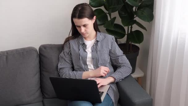 Στοχαστική Ενδιαφερόμενο Νεαρή Γυναίκα Κάθεται Στον Καναπέ Που Εργάζονται Φορητό — Αρχείο Βίντεο