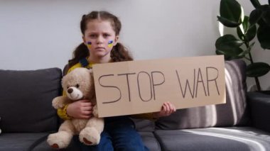 Ukraynalı küçük kız savaş anlaşmazlığını protesto ediyor. Elinde yazılı bir afiş var. Yazılı Savaş 'ı durdurun. Kriz, barış, saldırganlığı durdurun, Rus savaşına karşı çocuk
