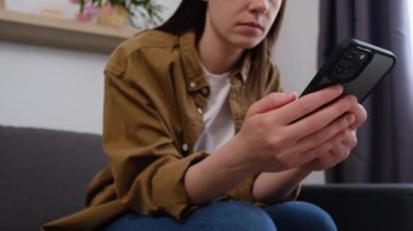 Gülümseyen beyaz kızın seçici odağı oturma odasındaki rahat kanepeye otur modern akıllı telefonlarda internete göz at, genç kadın evdeki rahat kanepeye uzan cep telefonu mesajlaşması ya da mesajlaşma kullanarak.