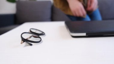 Uzaktan kumandayla çalışan ve ofis masasında oturan tanınmayan bir kadının seçici odak noktası. Genç kız gözlük takar, masaya oturur ve deniz fenerinde dizüstü bilgisayara bakar.