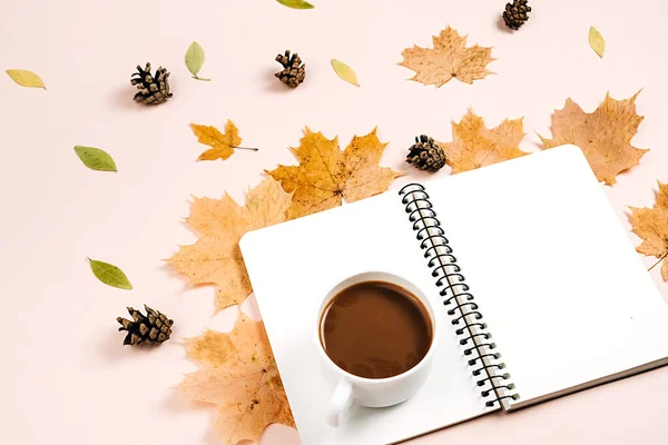 Stüdyoda kuru yapraklar, defter, çam kozalağı ve kahve fincanı ile birlikte solda bej arka planda, reklam için fotokopi alanı bulunuyordu. Şükran Günü, Sonbahar, Cadılar Bayramı konsepti. Yaratıcı bileşim