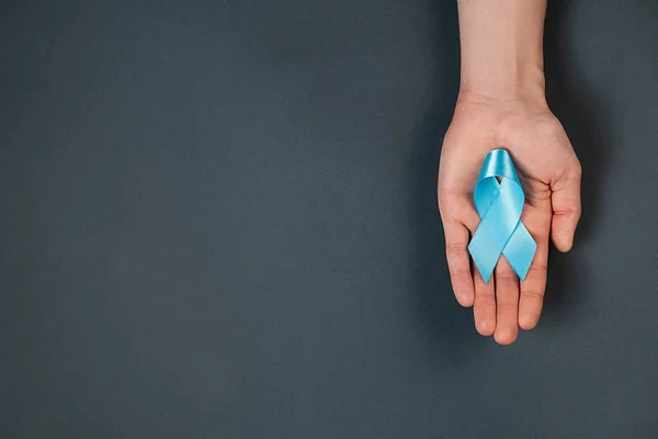 Close Male Hand Holding Blue Ribbon Awareness Grey Background Wall — Fotografia de Stock