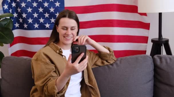 Smiling Young American Female Sitting Cozy Couch Usa Flag Waving — Stock Video