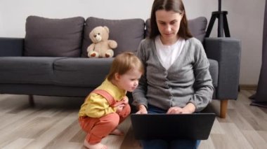 Gülümseyen anne ve küçük kız ekranda oturup eğleniyor. Mutlu anne, çocuklara dizüstü bilgisayarı kullanmayı öğretiyor. Çizgi film izliyor ya da bilgisayar başında video görüşmesi yapıyor.