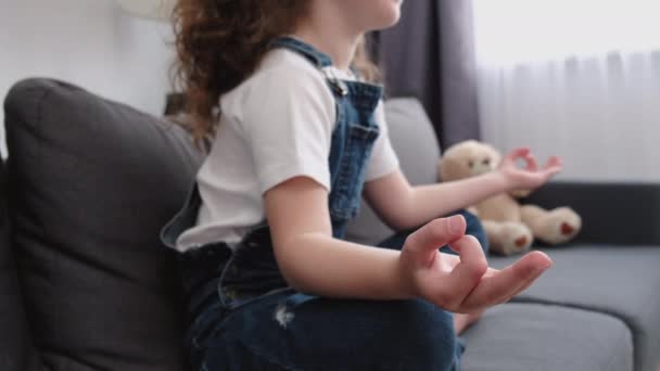 沉着的小女孩有选择地集中精神 双腿交叉地坐在沙发上 手指头交叉 和蔼可亲 内心和谐 冥想瑜伽时间 精神保健概念 — 图库视频影像