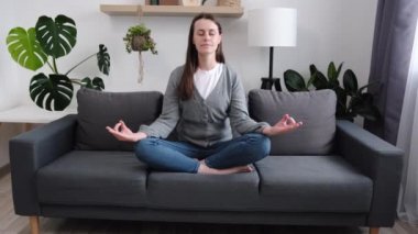 Stres yok, denge konsepti. Sakin, genç, beyaz bir kadın oturma odasındaki rahat koltukta bacak bacak üstüne atarak oturur. Gözler kapalı meditasyon yapar. İç ahengi hisseder, bilinci ve farkındalığı geliştirir.
