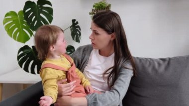 Endişeli genç anneyi teselli eden, teselli eden, ağlayan küçük kız çocuğunu kucaklayan, ona bakan ve koruyan kanepeye oturan, endişeli yetişkin anneyi seven, üzgün, küçük kızı teselli eden, çocuk konsepti.