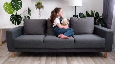Evdeki oturma odasında koltukta oturan, depresyonda olan, travma geçiren üzgün, küçük bir kızın portresi. Çocukluk sorunları, istismar, aile kavramında