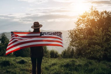 Arka planda destansı yaz dağlarında dikilen şapkalı esmer kadının güzel gün batımında ya da gün doğumunda gururla ABD bayrağını havada tutar. Vatanseverlik ve özgürlük kavramı