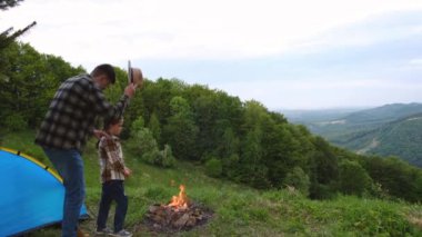 Sevgi dolu genç baba ve küçük kız kamp ateşinin yanında ve dağların arkasında mavi çadırda oturuyorlar. Önemseyen baba ve çocuk doğanın tadını çıkarır. Hafta sonu kaçamağı, sakinlik ve farkındalık konsepti