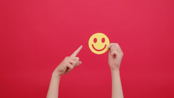 黄色の幸せな笑顔の顔を保持する女性の手の閉じる 良いフィードバック評価と肯定的な顧客レビュー Okのサインを示す 満足度調査 精神健康評価 赤の背景に隔離 — ストック動画