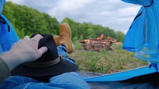 在阴天 一对恋人躺在帐篷里 从里面欣赏绿色的森林和温暖的篝火 露营浪漫旅行的概念游牧民族千年生活方式 — 图库视频影像