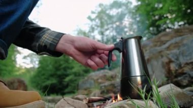 Ormandaki tanınmayan iki kişi kamp ateşinin yanına sıcak kahve döker, doğada rahatlar sıcak içeceklerle ısınarak eğlenceli vakit geçirir genç çiftler hafta sonlarını kamp yaparak geçirirler.