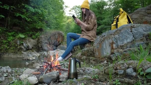 Dağ Nehri Şenlik Ateşi Yakınında Taşın Üzerinde Oturan Akıllı Telefondaki — Stok video