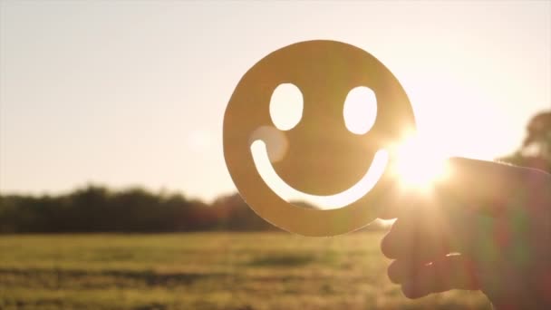 驚くべき日没や日の出を背景に黄色の幸せな笑顔の顔を保持する女性の手の閉じる 良いフィードバック評価と肯定的な顧客レビュー 満足度調査 精神健康評価 — ストック動画