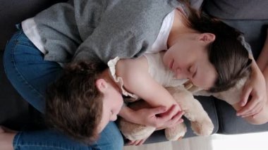 Sevgi dolu genç bir anne ve tatlı bir kızın evdeki rahat koltukta uzanması, rahat bir annenin küçük kız çocuğuna destek olması, sevgi ve şefkat göstermesi. Mutlu aile kavramı