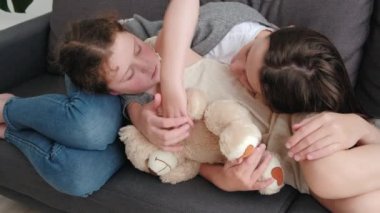 Rahatlamış, küçük, tatlı bir kız. Genç bir anneye sarılıyor. Rahat bir kanepede dinleniyor.
