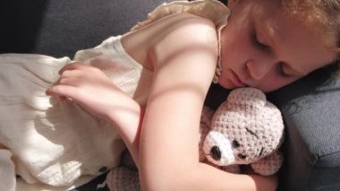Sweet dreams. Cute little girl sleep dream nap on cozy couch lying in comfortable pose with fluffy bear. Close up of tired child kid fall asleep on comfy sofa in silent living room after active day